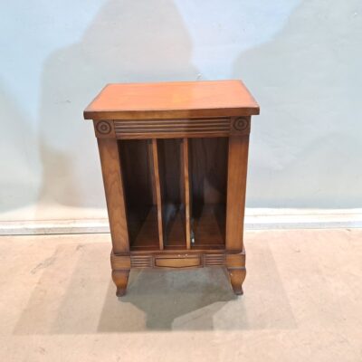Mesa auxiliar de estilo clásico o vintage, diseñado con tres compartimentos verticales abiertos y patas curvas. Por sus características y dimensiones aproximadas, este tipo de mueble se utiliza comúnmente como mesita auxiliar, revistero o para organizar discos de vinilo. Alquiler para eventos, publicidad, series, películas.