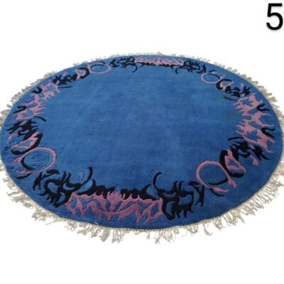 Alfombra redonda marroquí de color azul intenso con motivos decorativos en lila y flecos en el borde alquiler para eventos, publicidad, peliculas y series
