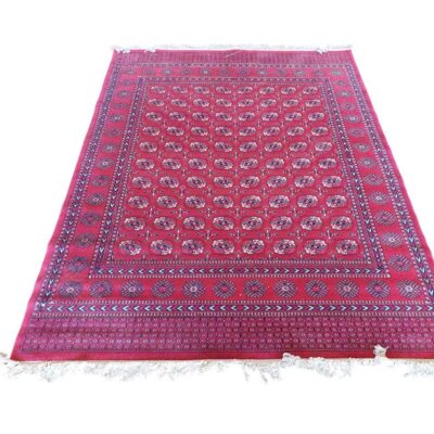 Alfombra afgana de estilo Bukhara con un diseño geométrico tradicional en color rojo alquiler para eventos, publicidad, peliculas y series