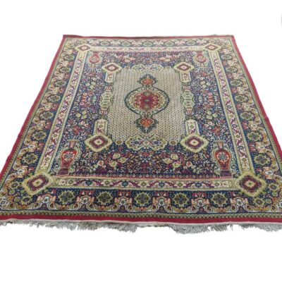 Persian style carpet with a traditional central medallion design and geometric motifs in red, blue and beige colours for rent for events, advertising, films and series.