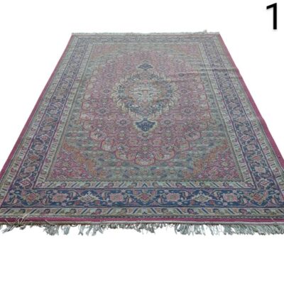 Alfombra es una pieza vintage de lana anudada a mano, posiblemente de estilo turco o persa, con patrones florales tradicionales en tonos rosa y azul. alquiler para eventos, publicidad, peliculas y series