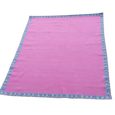 Cobija de color rosa con un borde estampado colorido  alquiler para eventos, publicidad, series y peliculas